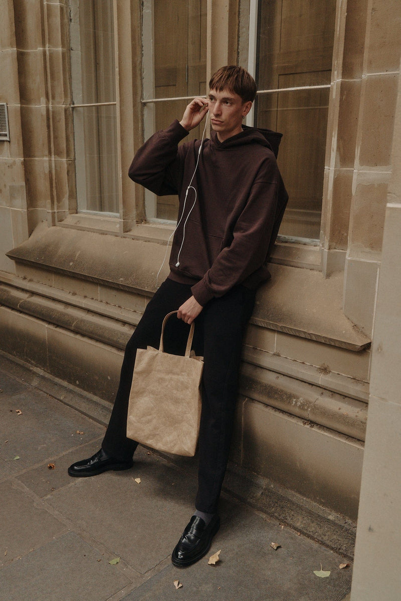 Model in an espresso hooded jacket and black trousers on a city street