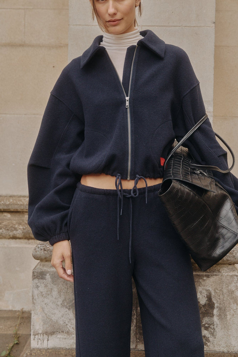 Model in a navy CoolBlend collared jacket beside sandstone columns