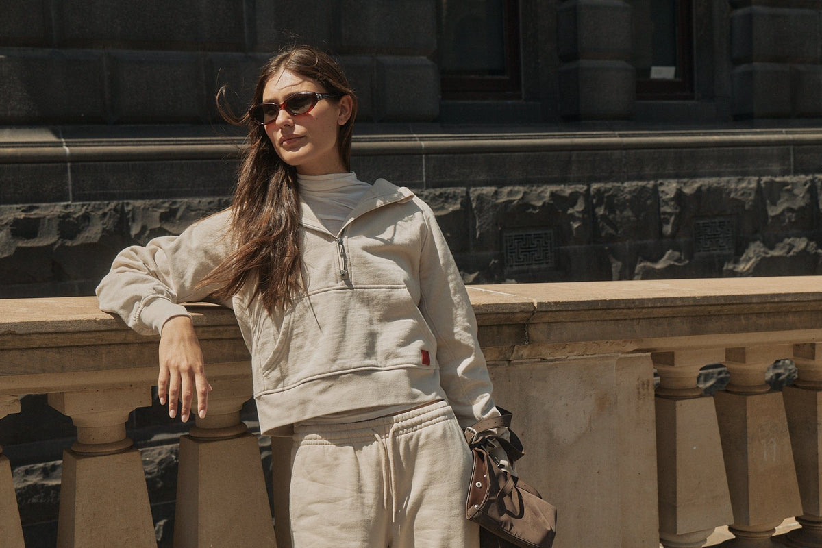 Model in a cream half-zip hoodie and matching sweatpants outdoors