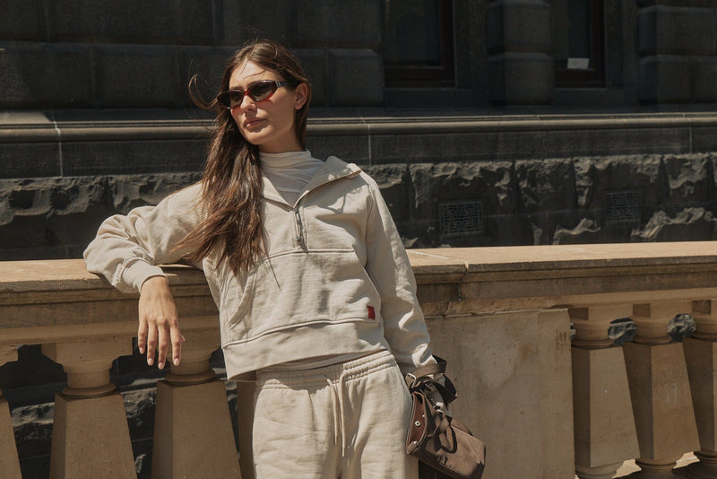 Model in a cream half-zip hoodie and matching sweatpants outdoors
