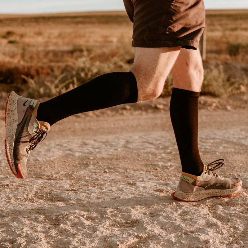 Model walking a gravel path in boots and black knee-high socks
